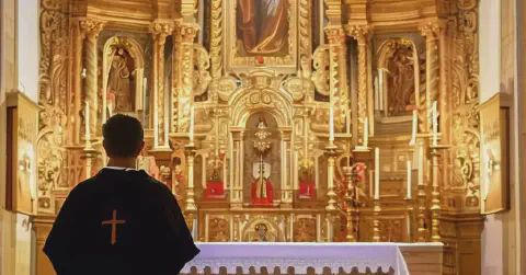 A Priest Standing By The Altar Inside The Iglesia Of Santa Maria Los Arcos Spain